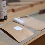 Furnierplatten werden mit Leim bestrichen